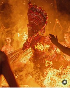 people standing around a fire with an elaborate mask on