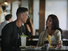 a man and woman sitting at a table with food