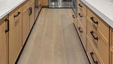 a kitchen with wooden cabinets and stainless steel appliances in the center, along with white marble counter tops