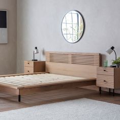 a bed with wooden slats and drawers in a white room next to a round window