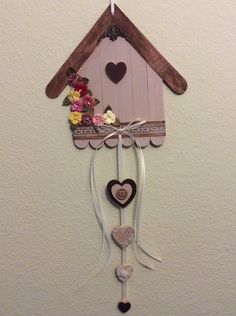 a bird house with hearts hanging from it's side and flowers on the outside