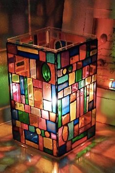 a lamp that is sitting on the floor in front of a wall with colorful tiles