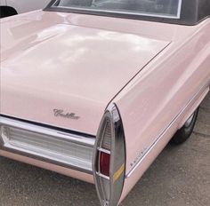 an old pink car parked in a parking lot