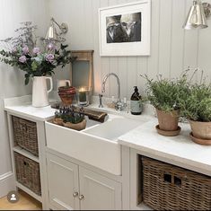 a kitchen sink with baskets on the counter and flowers in vases next to it