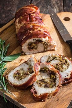 meatloaf wrapped in bacon and garnished with herbs on a cutting board