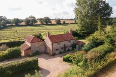 an aerial view of a country house surrounded by hedges and trees in the distance is a field