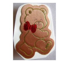 a pink teddy bear with a red bow on it's neck and chest, embroidered onto a white surface