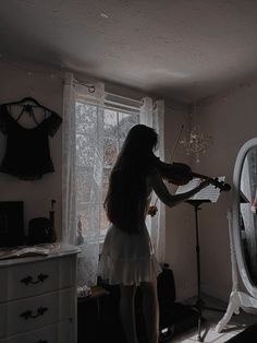 a woman standing in front of a mirror holding a violin