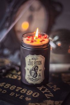 a lit candle sitting on top of a black book next to a clock and other items