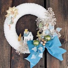 a white wreath with blue ribbon and angel decorations