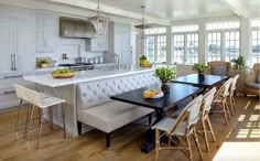 a kitchen and dining room with white walls, hardwood floors and an island in the middle