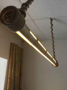 a light fixture hanging from the ceiling in an office area with ropes and lights attached to it