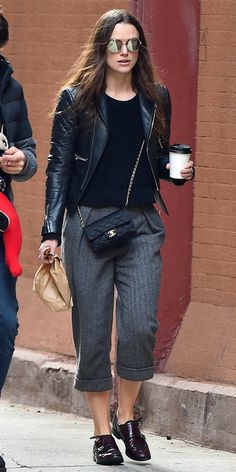 a woman walking down the street with a cup of coffee in her hand and another person holding a purse