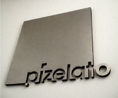 a metal sign that reads pizzeria on the side of a white wall with black lettering