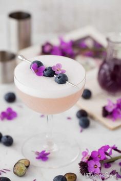 a drink with blueberries and purple flowers in it