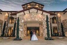 a bride and groom standing in front of a large stone building with columns on each side