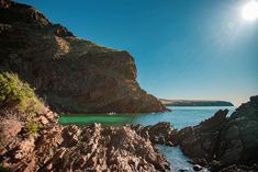 the sun shines brightly over some rocks and water