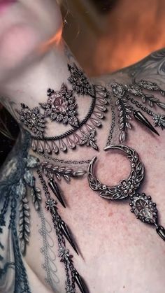 a woman's chest is adorned with black and silver jewelry, including feathers and chains