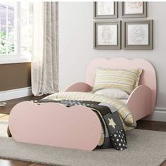 a child's bedroom with a pink bed and white carpeted flooring, framed pictures on the wall