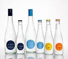 six bottles with different labels on them are lined up in front of each other, one is empty