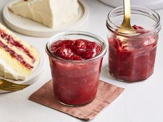 two jars filled with jam sitting on top of a table next to cakes and desserts