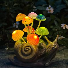 a snail lamp with glowing mushrooms in it's shell on the ground next to flowers