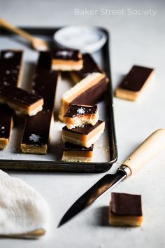 there are several pieces of dessert on the tray next to a knife and spoons