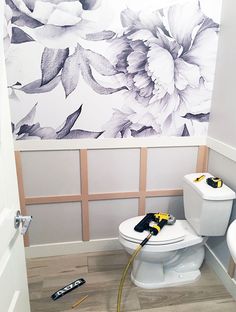 a white toilet sitting in a bathroom next to a wall with flowers painted on it