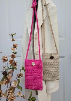 two crocheted purses are hanging on a coat rack next to a plant