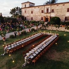 a long table set up outside in front of an old building with lights on it