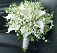 a bridal bouquet sitting in the back seat of a car with white flowers and baby's breath