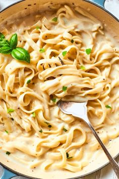 a skillet filled with pasta and topped with fresh basil garnished with parsley