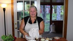 a woman in an apron preparing food on a wooden table