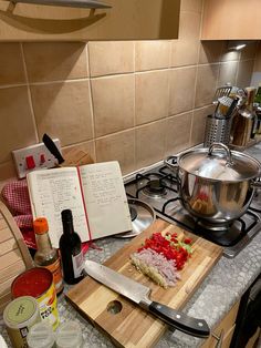 a cutting board with chopped vegetables on it next to a cookbook and stove top