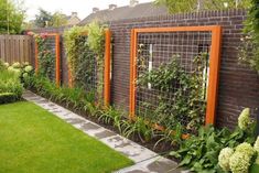 an outdoor garden with green grass and plants on the side of a brick fenced in area