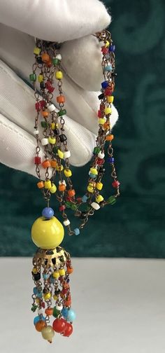 a close up of a person wearing a necklace with beads and charms on it's fingers