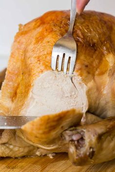 a person holding a knife and fork over a turkey