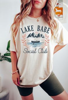 Lake Babe Social Club Shirt Welcome to our shop! Please note the models shown in the pictures are wearing 1 or 2 sizes up, if this is your desired look, please keep sizing in mind.  All styles shown feature Comfort Colors C1717 an ultra-soft pigment dyed shirt featuring a comfy relaxed feel with 100% Cotton. Other details   .: 100% ring-spun cotton .: Heavy fabric (6.1 oz/yd² (206.8 g/m .: Relaxed fit .: Sewn-in twill label If you need any helping placing an order, please message me and I will b Cotton Camp Shirt With Letter Print For Camping, Casual Graphic Print Camp Shirt, Cotton Camp Shirt With Letter Print For Outdoor, Pre-shrunk Cotton Camp Shirt For Outdoor Activities, Casual Camp Shirt With Letter Print And Relaxed Fit, Casual Crew Neck Camp Shirt For Outdoor Activities, White Letter Print Shirt For Camping, Casual Pre-shrunk Camp Shirt For Camping, Pre-shrunk Cotton Camp Shirt For Camping