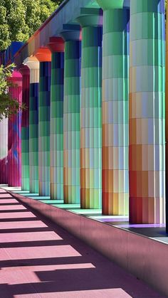 a row of colorful columns on the side of a building with trees in the background