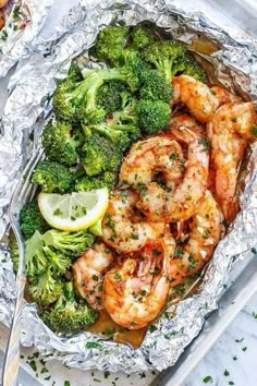 shrimp and broccoli wrapped in foil with lemon wedges on the side for garnish