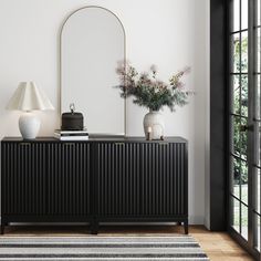 a black and white sideboard with vases on it next to a large mirror