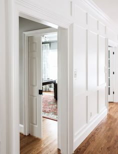 an open door leading to a living room with hardwood floors and white paint on the walls