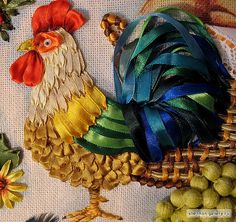 a colorful rooster sitting on top of a table next to grapes and other items in a basket