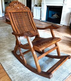 a wooden rocking chair sitting on top of a rug in front of a fire place