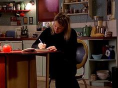 a woman sitting at a kitchen table writing