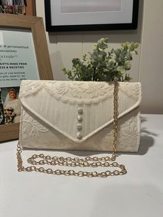 a white purse sitting on top of a table next to a vase with flowers in it