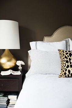 a leopard print pillow on top of a bed with white sheets and black polka dot pillows