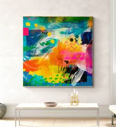 an abstract painting hangs on the wall above a coffee table