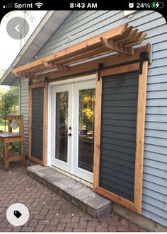 an outside patio with a wooden pergolan and white doors on the side of it