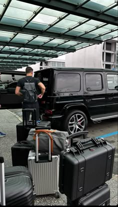 a man standing next to a bunch of luggage in front of a black truck with its door open